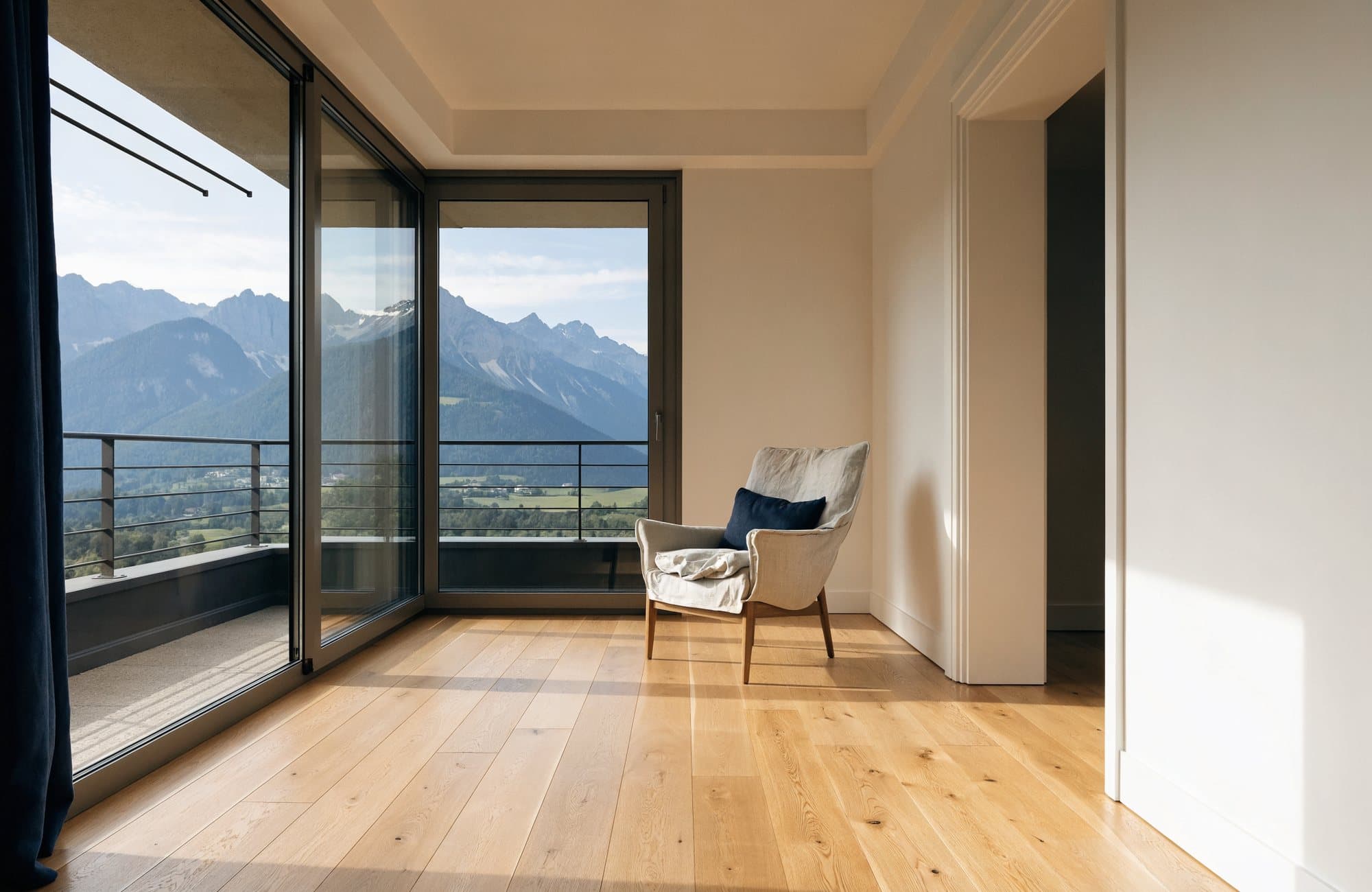 Séjour lumineux d’un appartement neuf ouvert sur un balcon avec vue sur les montagnes